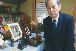 必勝氏の写真の前で