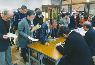 必死でサインしてます