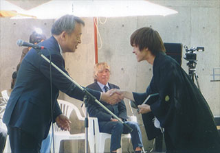 新成人に手紙を渡し、握手する